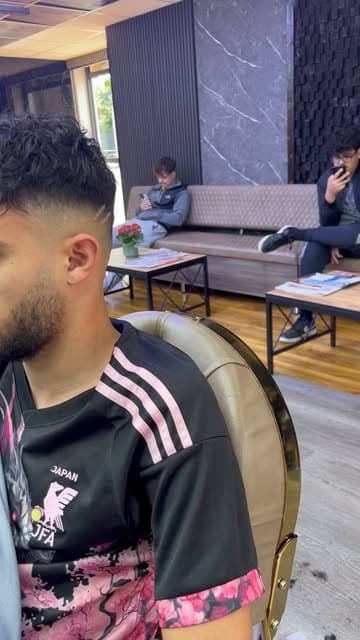 Skin fade with a hard part and textured curly top, cut at Nwah Trims, Telford